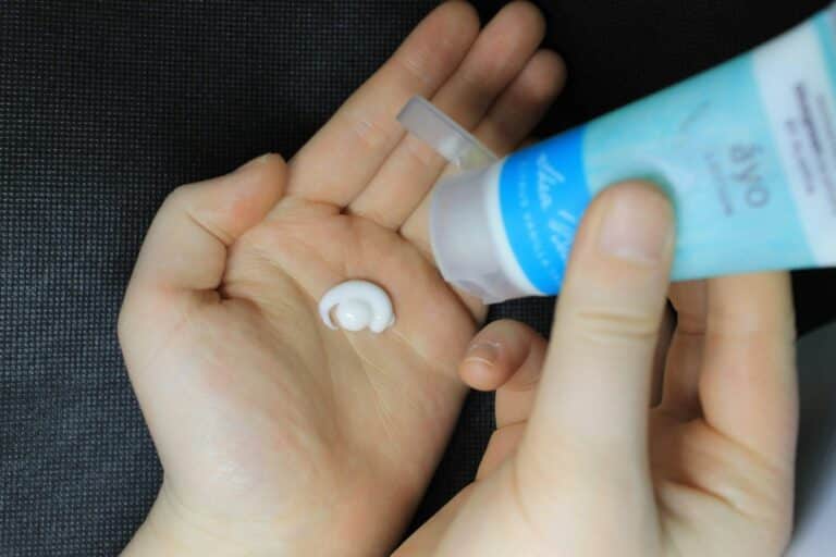 Applying moisturizer to hand from a tube.